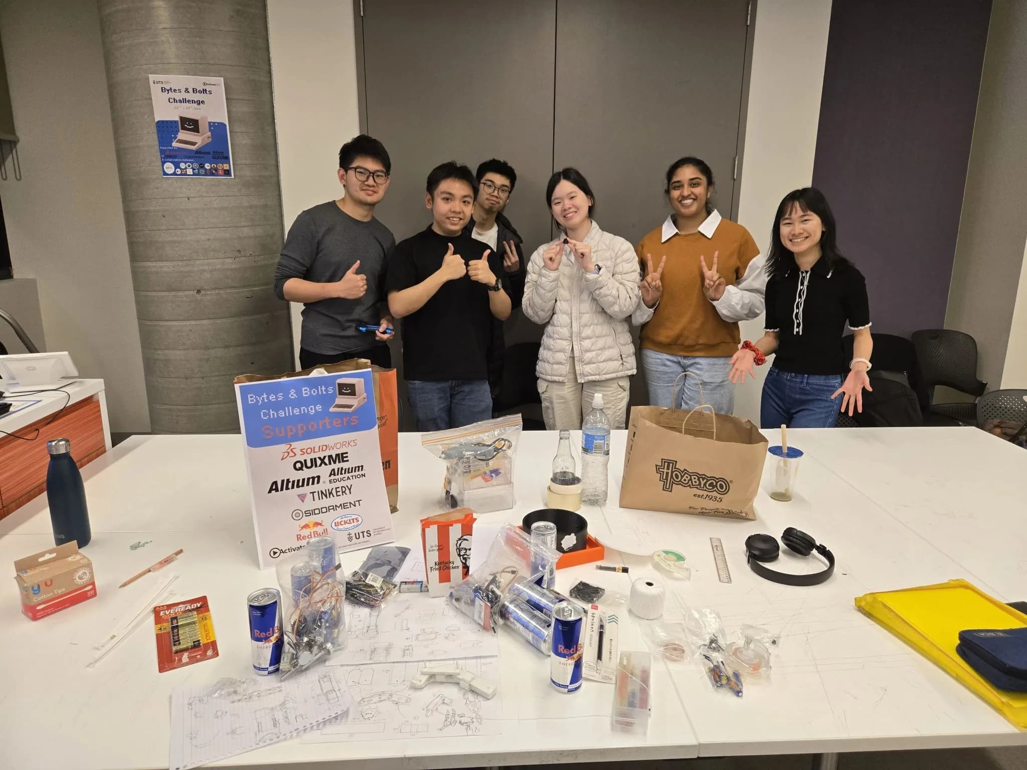 A Bytes & Bolts Challenge team at their build table, beside a supporter board listing QUIXME
